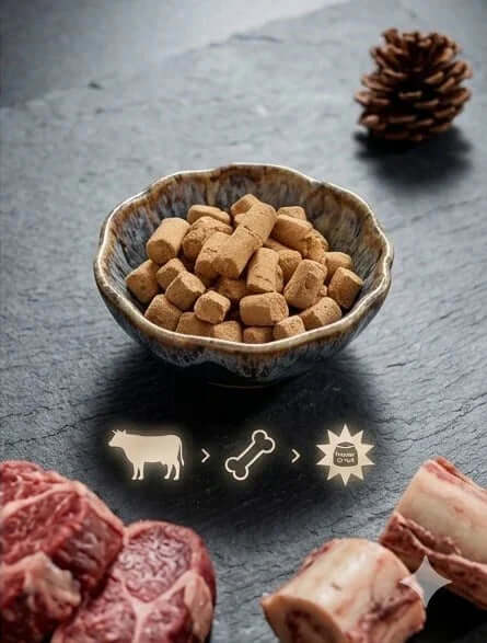 PawDry Freeze-Dried Beef Raw Meaty Bone (RMB) 100g in a bowl with raw beef cuts and bone on a slate background.