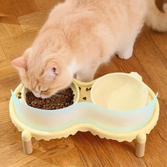 Cat eating from elevated double bowl feeder with food and water compartments on wooden floor