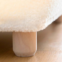 Close-up of a fluffy white cushion on a wooden stool.