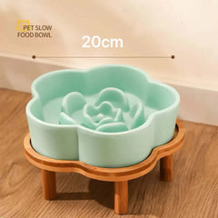 Mint green flower-shaped ceramic slow feeder bowl for cats and dogs on a wooden stand.