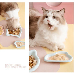 Fluffy cat eating from stylish ceramic bowls, different shapes for cat food and wet meals