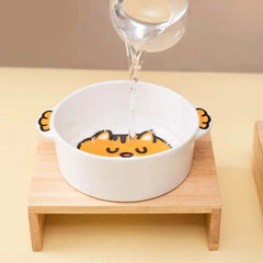 Cute cat-themed ceramic pet bowl with wooden stand, being filled with water for cats or dogs.