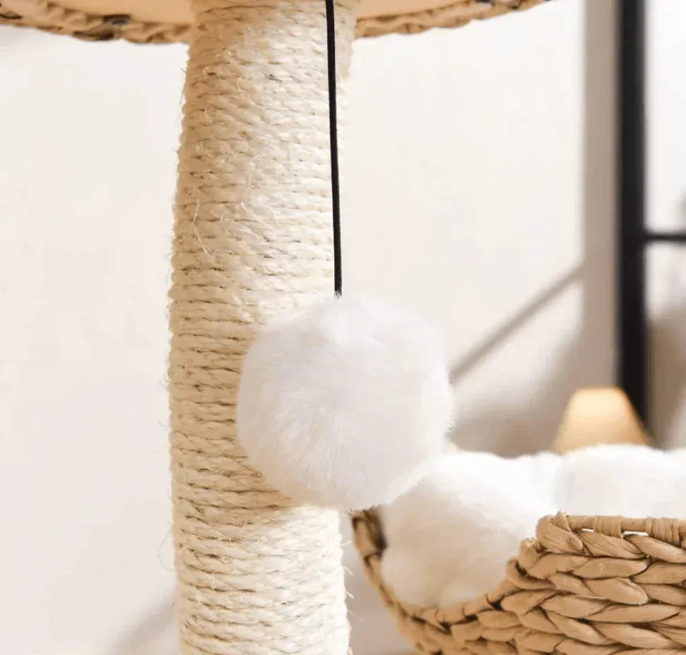 White fluffy pom-pom cat toy hanging from sisal scratching post with woven basket