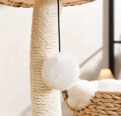 White fluffy pom-pom cat toy hanging from sisal scratching post with woven basket