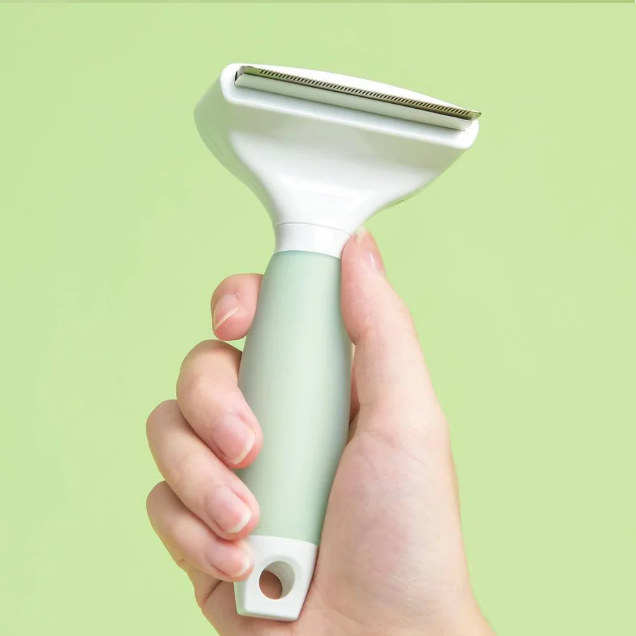 Michu Round-Head Grooming Dog/Cat Brush & Shedding Rake Bundle held in hand against a green background.