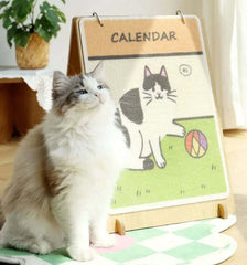 Fluffy cat beside cute cat-themed calendar on wooden stand, perfect for pet lovers’ home decor