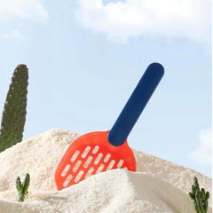 Orange cat litter scoop with blue handle in white litter, desert cactus background