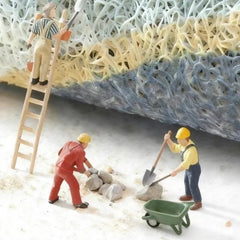 Miniature figurines working on a textured surface, depicting a construction scene with a ladder and wheelbarrow.