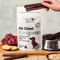 THE PAW GROCER Air-Dried Kangaroo Dog Training Straps 100g packaging with training straps on a wooden table.