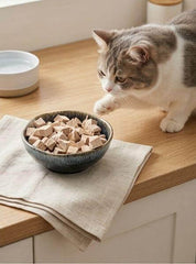 PawDry Freeze-Dried Duck Bites Pets Treats 100g in a bowl with a cat reaching for them.