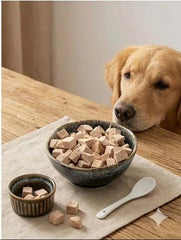 PawDry Freeze-Dried Duck Bites Pets Treats 100g in bowls with a golden retriever dog looking at them.