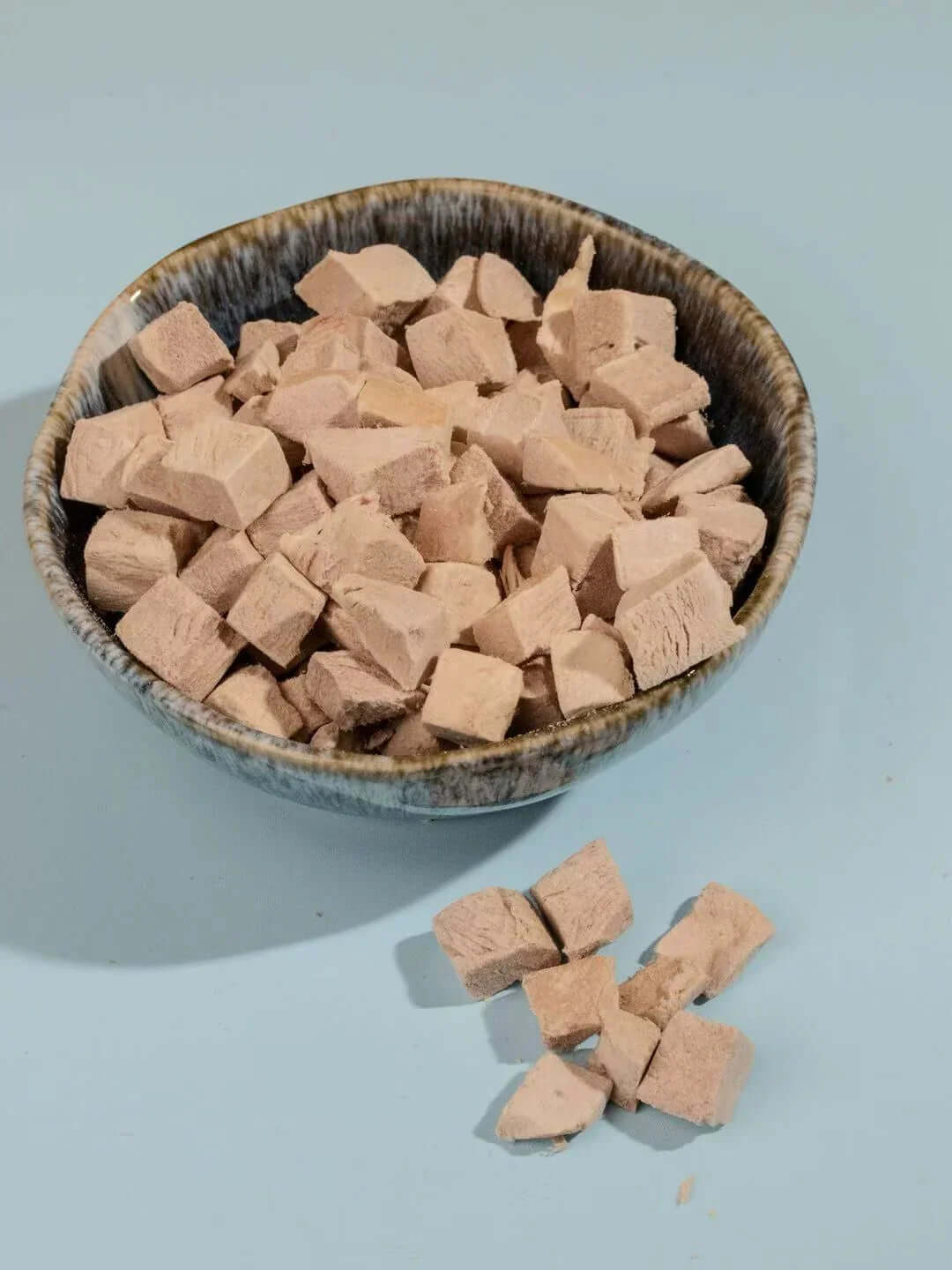 PawDry Freeze-Dried Duck Bites Pets Treats 100g in a ceramic bowl, showcasing natural pet snacks.