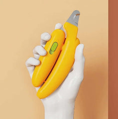 Yellow banana-shaped pet nail clipper with green safety guard, held in white hand against warm background