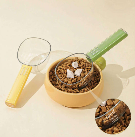 Dopamine Series 2-in-1 Pet Food Scoop with graduated measuring cup and bag sealing clip over pet food bowl.
