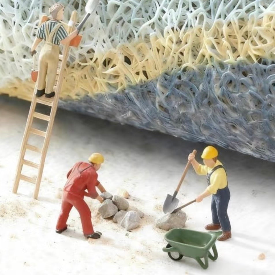 Miniature construction workers on a colorful texture background with tools and a wheelbarrow.