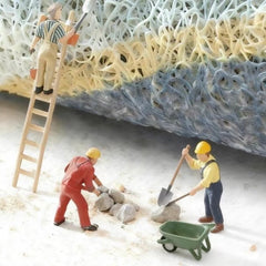 Miniature construction workers on a colorful texture background with tools and a wheelbarrow.