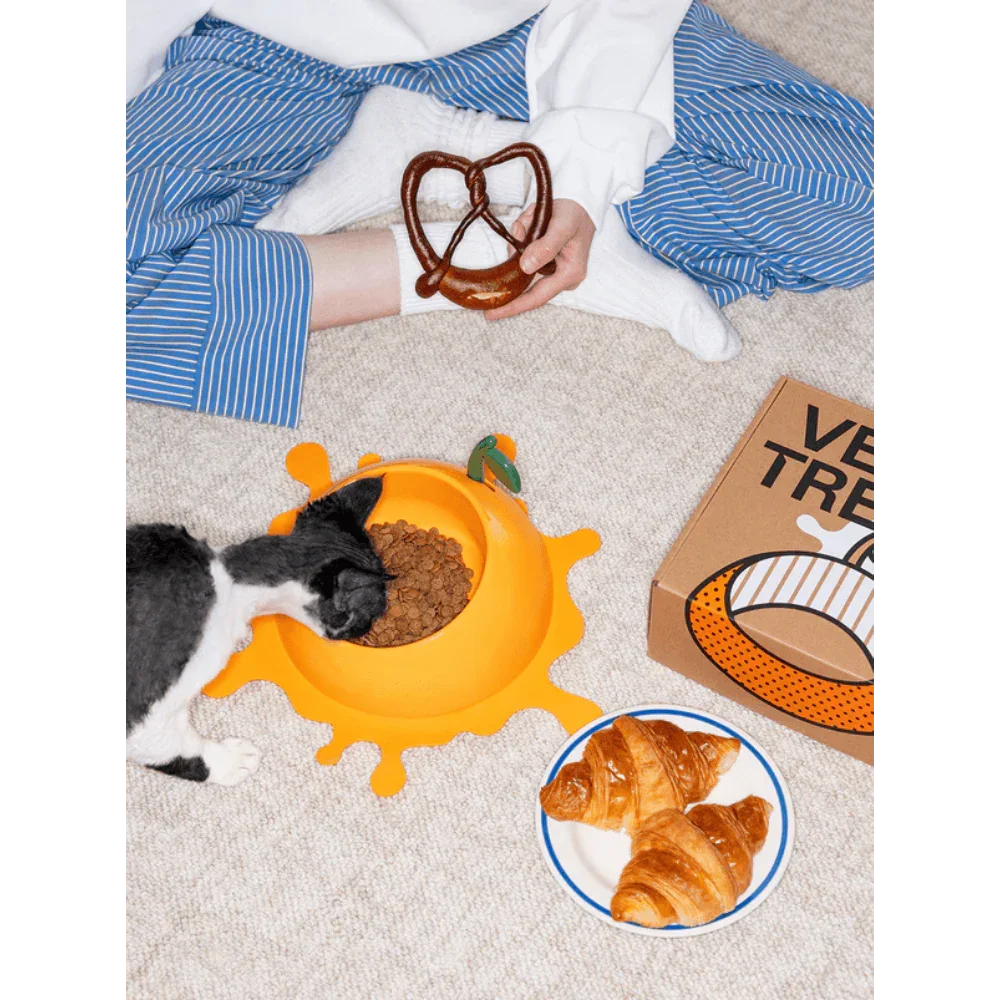 Vetreska Juicy Orange Pet Bowl & Spoon & Mat Set with cat eating from bowl and croissants nearby.